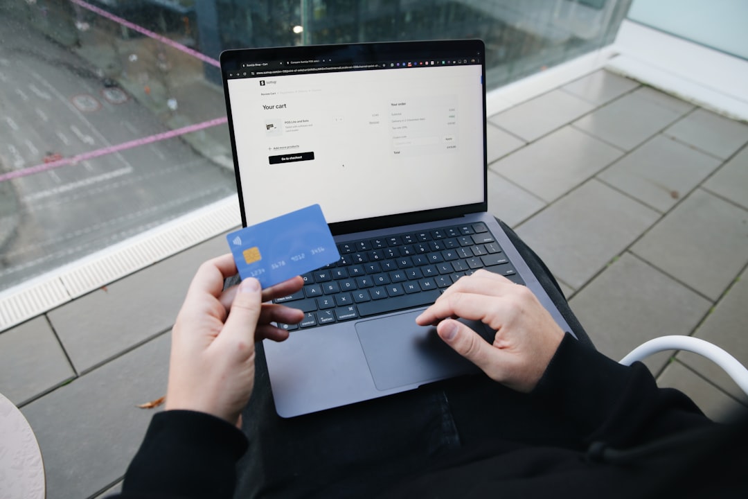 A person holding a credit card while completing an online purchase on a laptop