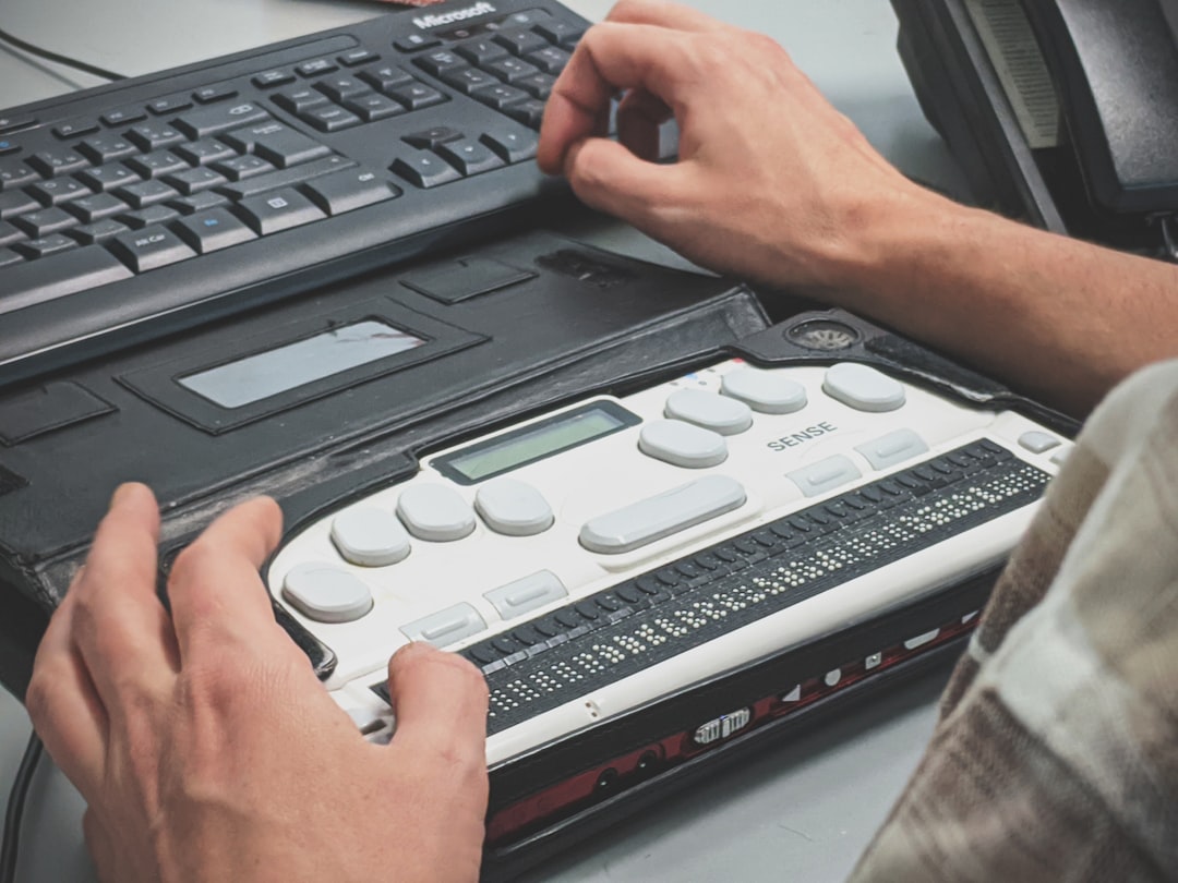 A person reading a refreshable braille display connected to a computer